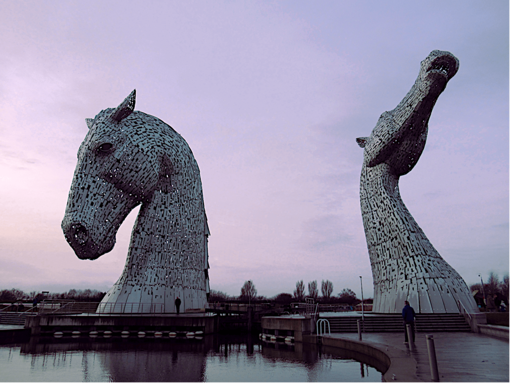 The two Kelpie heads in Falkirk are shown against a purple and pink dusk skyline. 