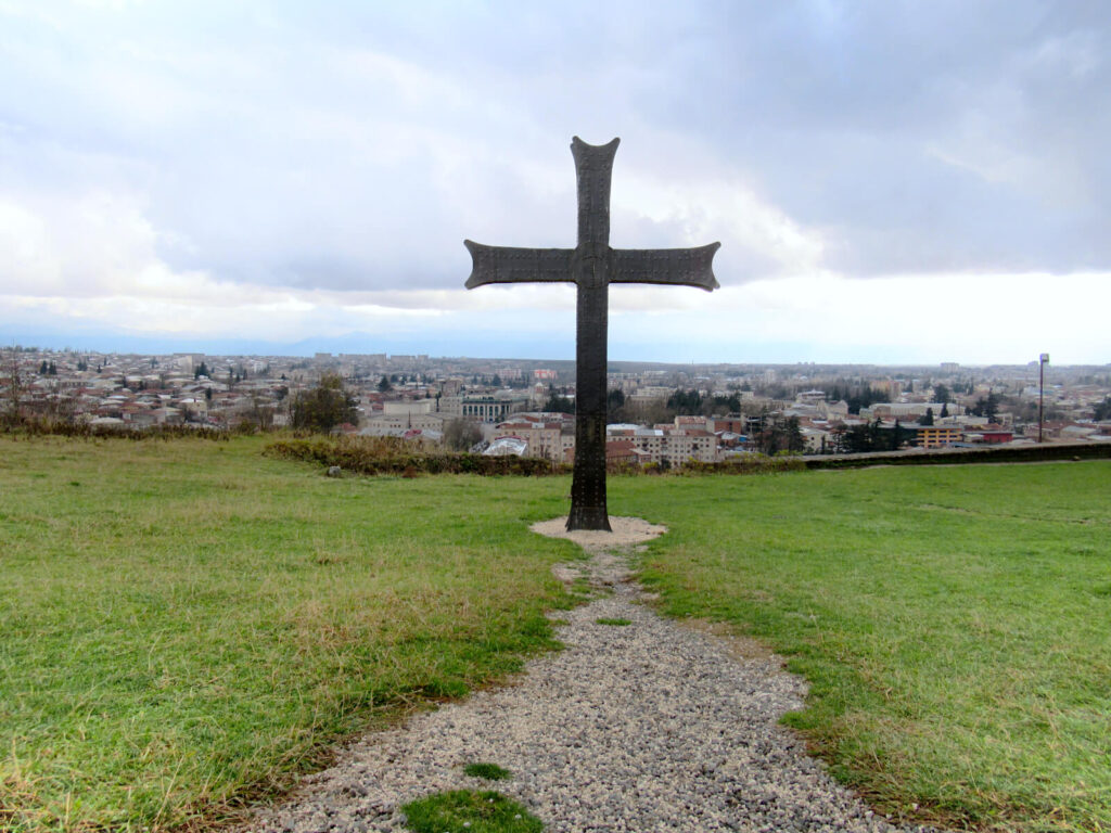 The view of Kutaisi from Bagrati Cathedral. A dark metal cross is in the forefront of the image overlooking the city.