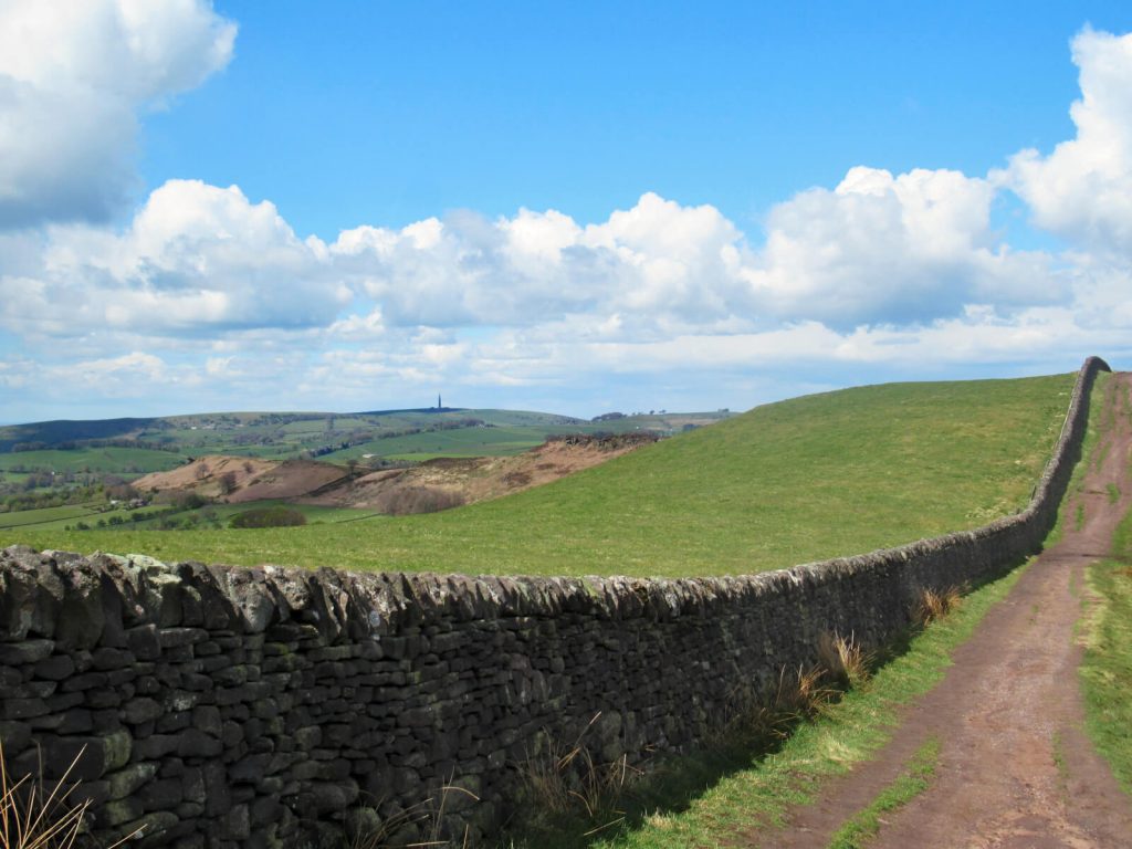 The rolling hills of the Staffordshire Peak District. Walk along the path as it follows the drystone wall to Lud's Church.