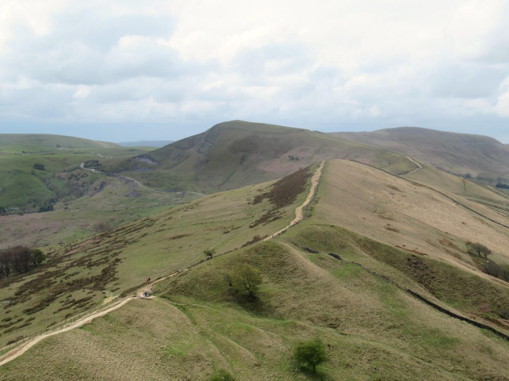 Looking west over the Great Ridge from the top of Back Tor, the path is clearly visible along the hill top as the ground drops off gently to either side. Mam Tor is in the background at the end of the pathway