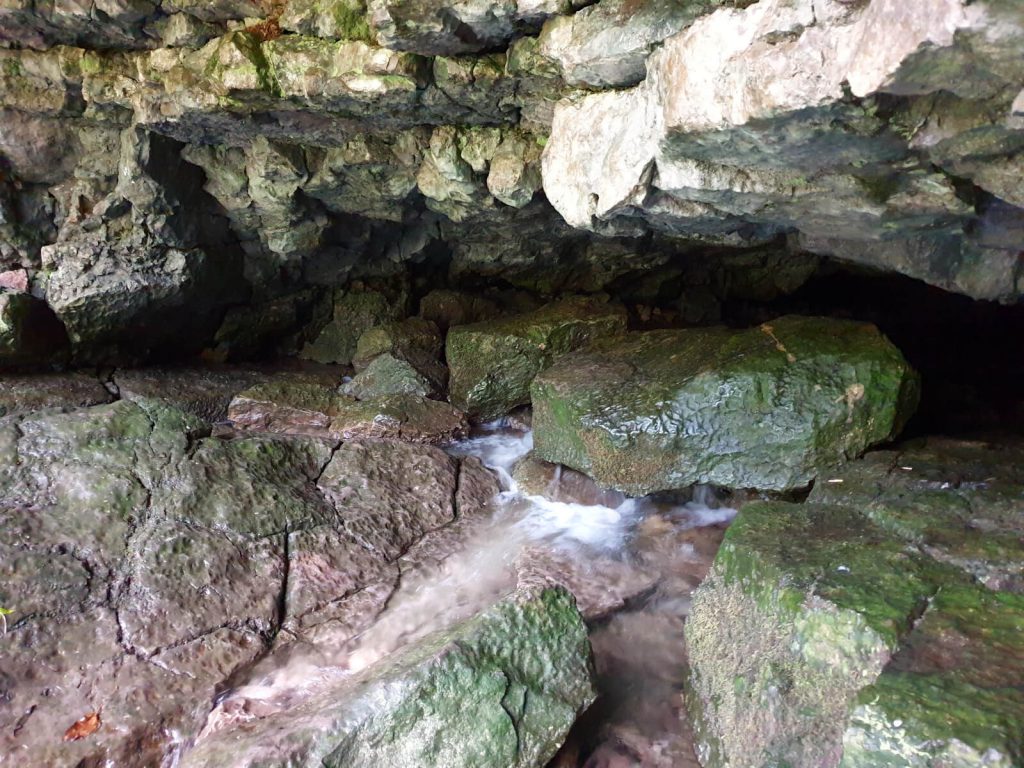 Inside the cave at the start of the River Lathkill, the water trickles or pours from beneath the rocks depending on the recent weather