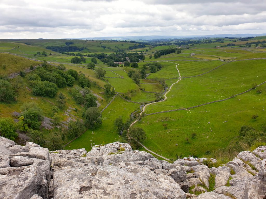 Beauty spot number 1 on this Malham circular walk! Looking over the edge of Malham Cove, the pathway from Malham Town to the cove is clearly visible and green fields run parallel on either side