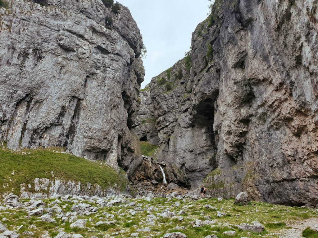 Beauty spot number 3 on the Malham Circular Walk! Gordale Scar, a waterfall over limestone rocks, is shown between two large cliff faces that tower above it