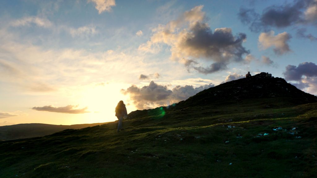 On the climb to the summit of Chrome Hill, the silhouette of Zoe is shown against the golden sky as the sun is setting over the Peak District