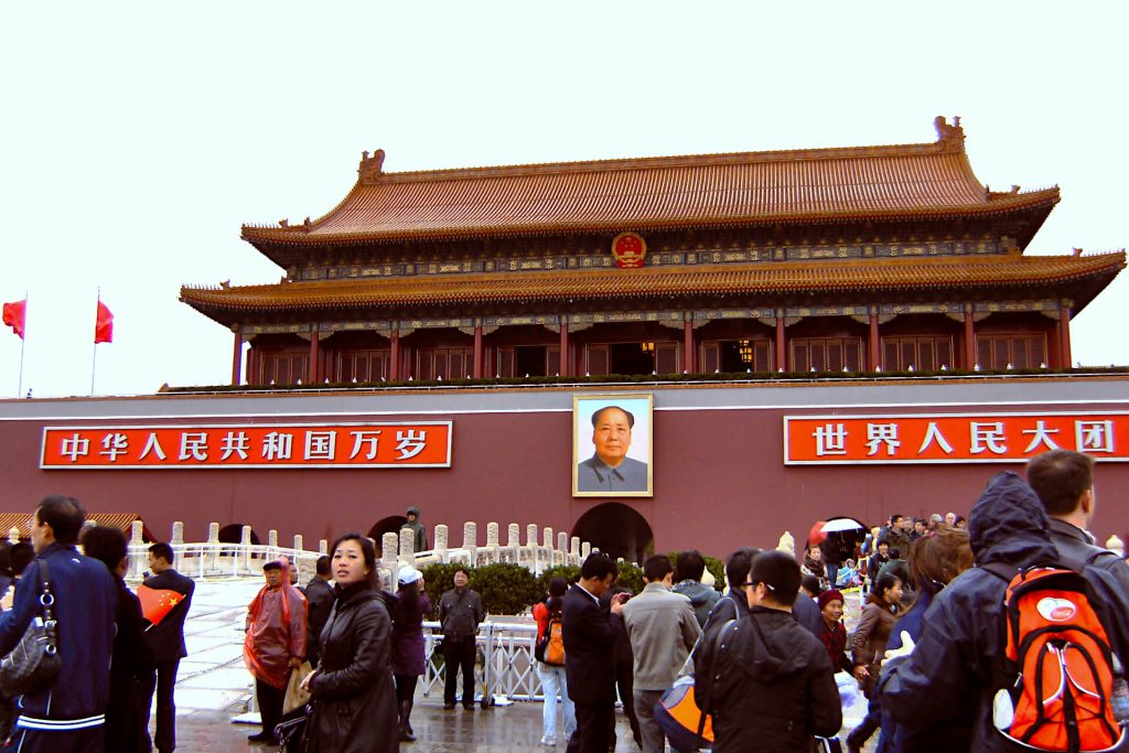 Forbidden City in Beijing, a pagoda style building with an image of Chairman Mao on the front, busy with tourists looking