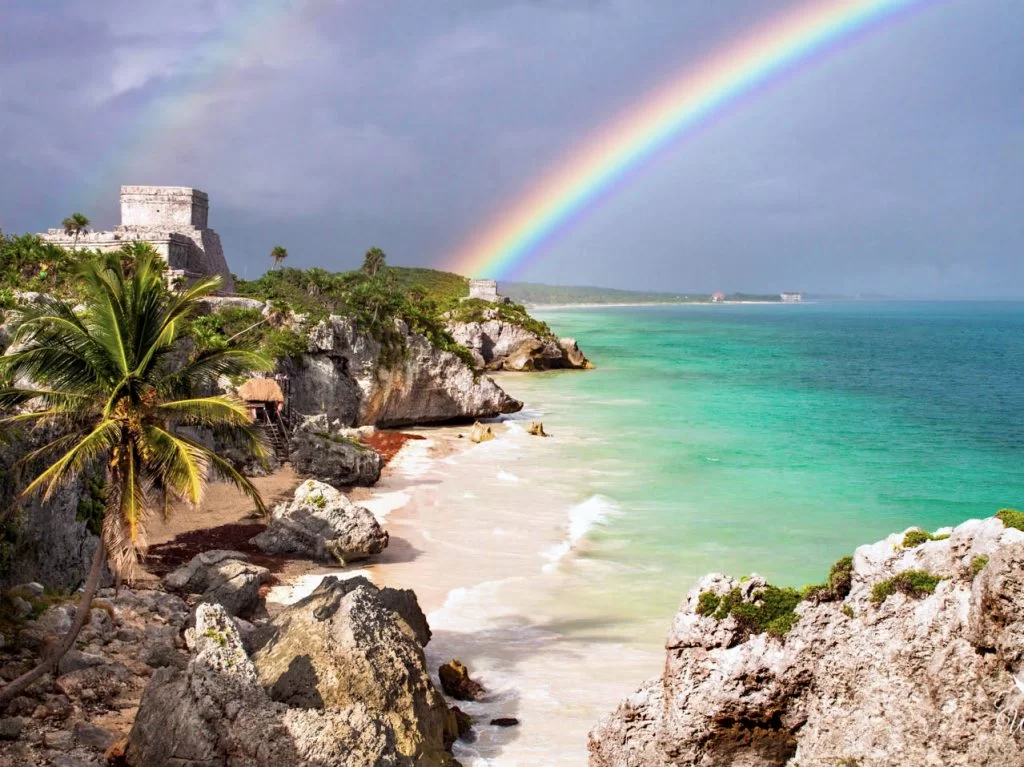 Looking over Tulum ruins on the Caribbean Sea with a rainbow over the top. A day trip from Playa del Carmen to Tulum Ruins is well worth it!