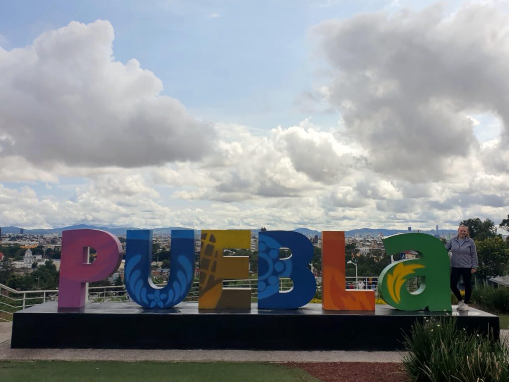 Zoe stood by the Puebla sign in the park next to the cable cars.