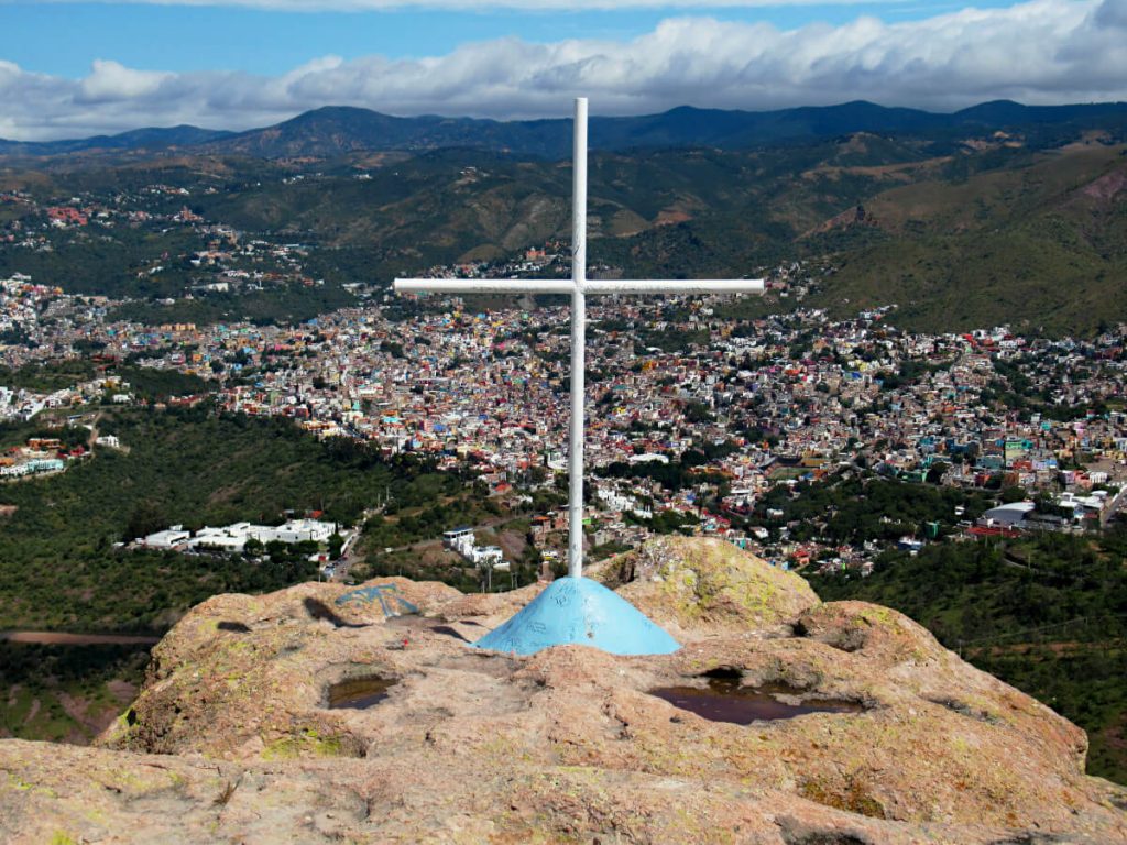 The city of Guanajuato sits behind the white cross at the top of Cerro de la Bufa