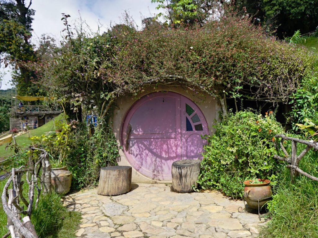 A pink-doored hobbit house in the side of the hill