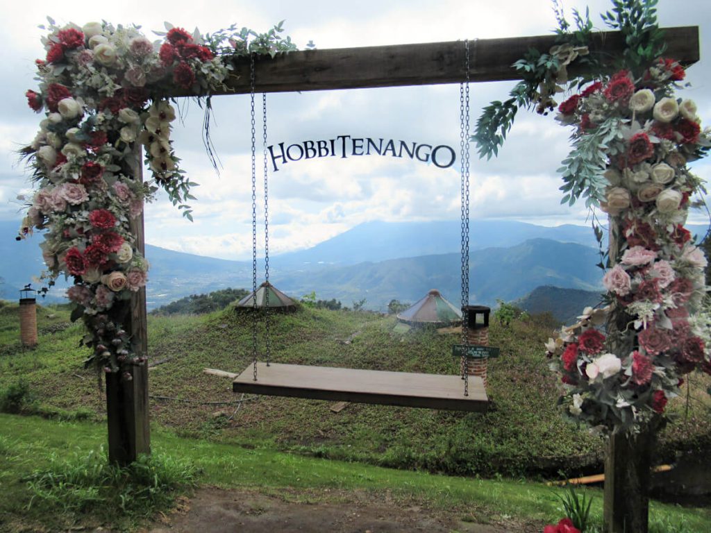 A swing with floral decorations and a Hobbitenango sign above it