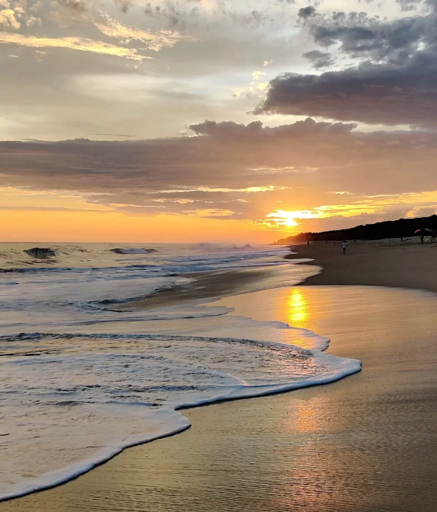 The sun sets over this Oaxaca beach, the waves lap the shore in the foreground