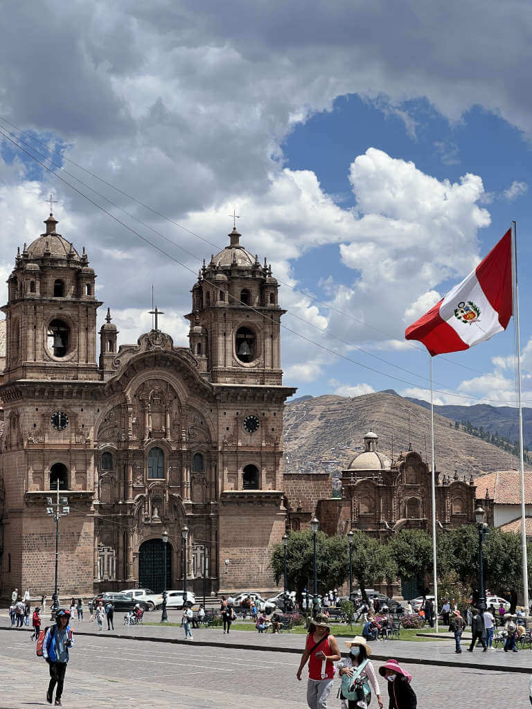 The main plaza in Cusco Peru with the cathedral and flag flying in the wind.