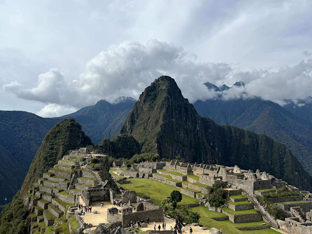 The postcard picture of Machu Picchu with Huayna Picchu behind and clouds hovering over the mountains in the distance.